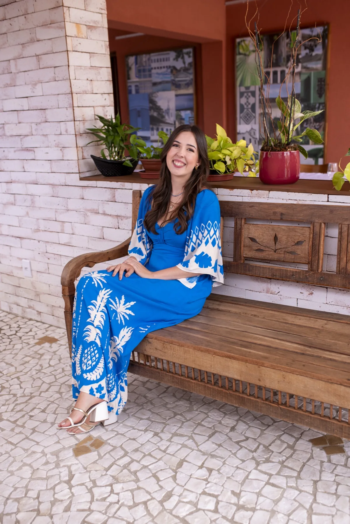 Tatiana Lucasin sorrindo, sentada em um banco de madeira