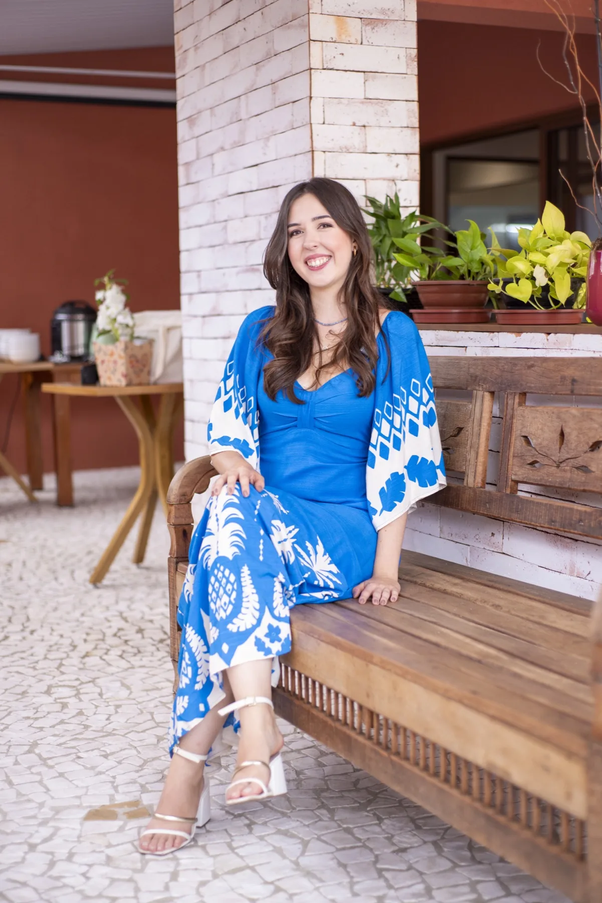 Tatiana Lucasin sentada em um banco de madeira, sorrindo